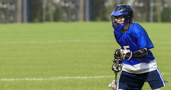 A  lacrosse player holding a stick on a field.