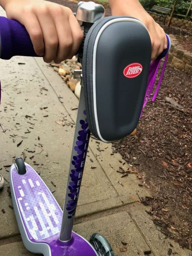 Hands on the handle bar of a purple Radio Flyer scooter.
