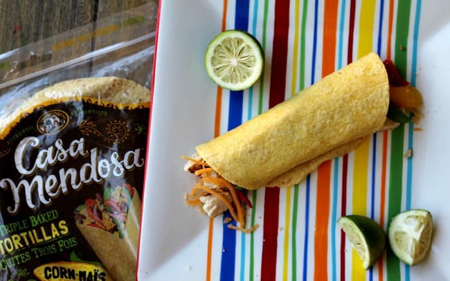 A soft shelled tortilla lying on a colorful towel.