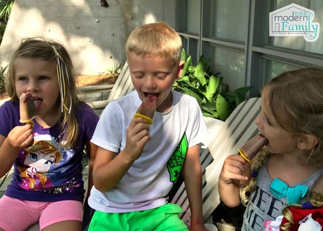 A little boy and two girls eating Chocolate covered strawberry banana freezer pops.