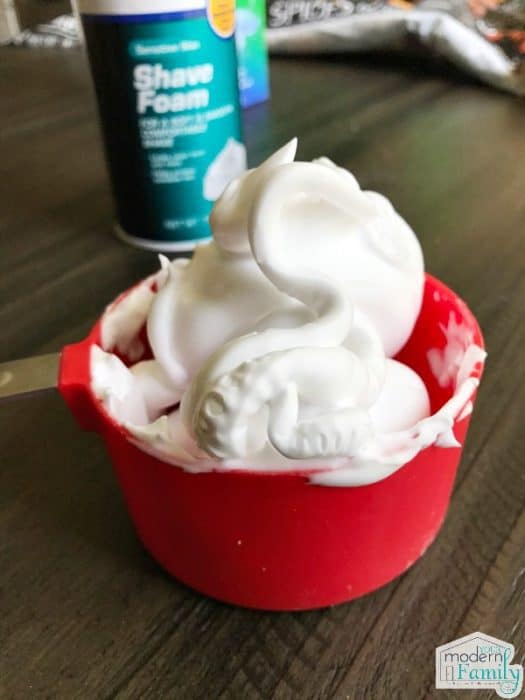 A cup of shaving cream in a red measuring cup.