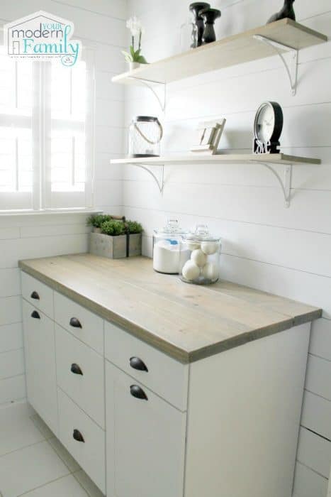 A laundry room with a cabinet and shelving above it. 