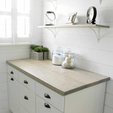 Laundry room with a counter and shelves above it.