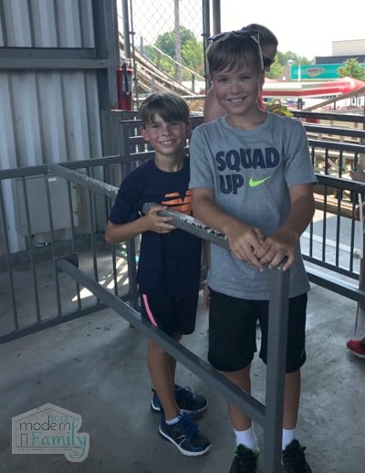 Two young boys standing in line at an amusement park.