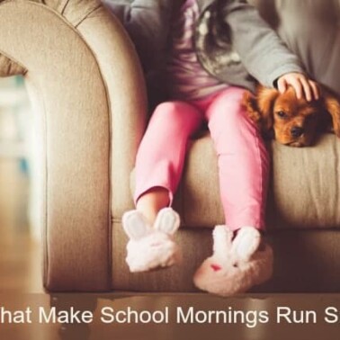 A young girl in bunny slippers petting a dog on the couch.