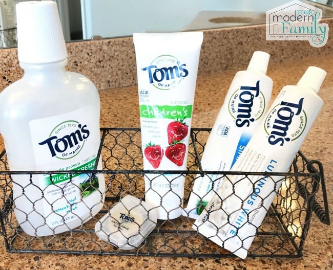 A close up of a variety of Tom\'s tooth paste, mouth wash and floss in a wire rack.