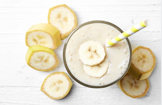 A banana smoothie with cut bananas around the glass.