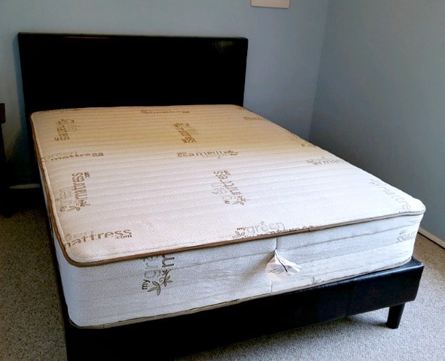 A mattress on a bed frame with head board.