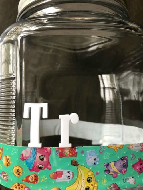 A glass jar with decorations and letters on it.