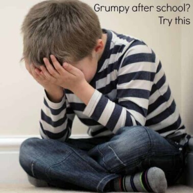A young boy sitting on the ground with his head in his hands.