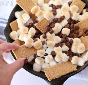 A black pan with graham crackers, marshmallows and chocolate chips.