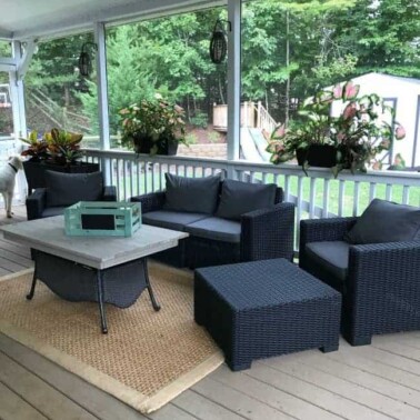 View of a screened in porch with furniture and a table.