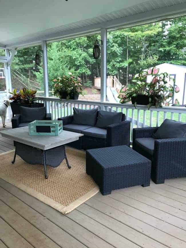 View of a screened in porch with furniture and a table.