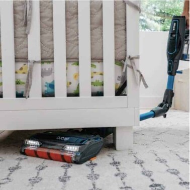 A Shark vacuuming under a crib.
