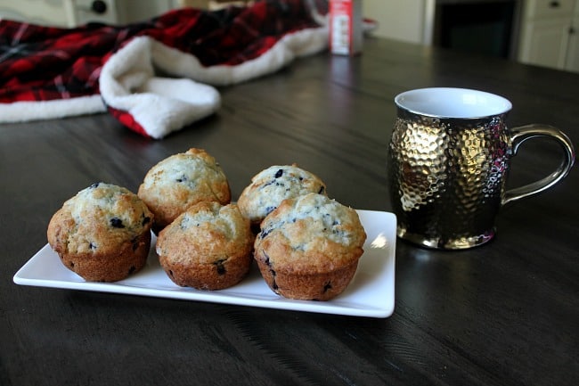 A tray of blueberry muffins with a copper cup sitting beside them.