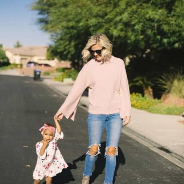 A woman and little girl holding hands walking down the road together.