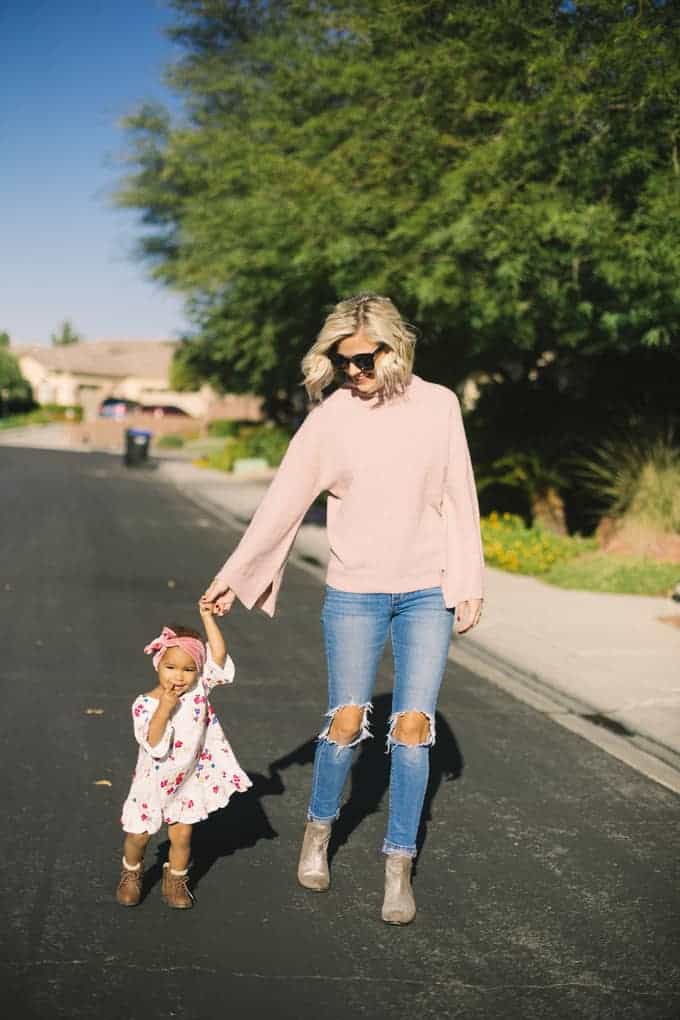 A woman and little girl holding hands walking down the road together.