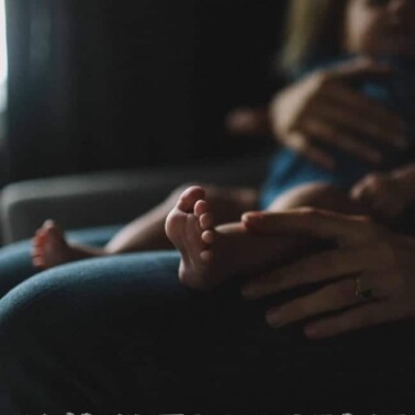 A person sitting in a chair holding a sleeping baby.
