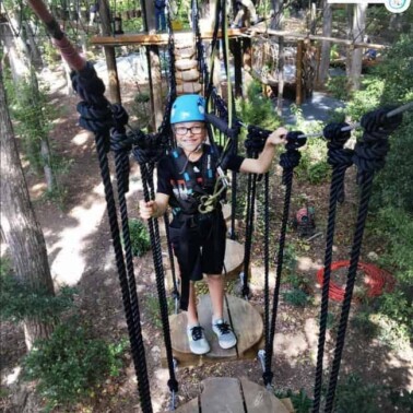 A young boy walking across a rope bridge.