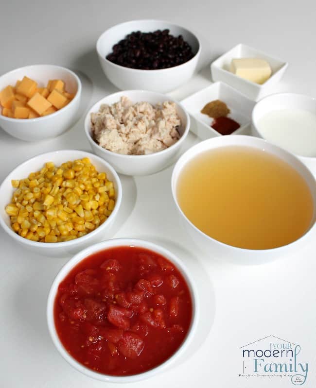 A variety of ingredients in white bowls to make Cheesy Crockpot Chicken Enchiladas.