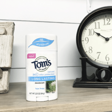 A container of Tom's deodorant sitting beside a clock.