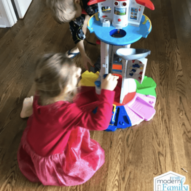 A little girl and a boy playing with a Paw Patrol Tower together.