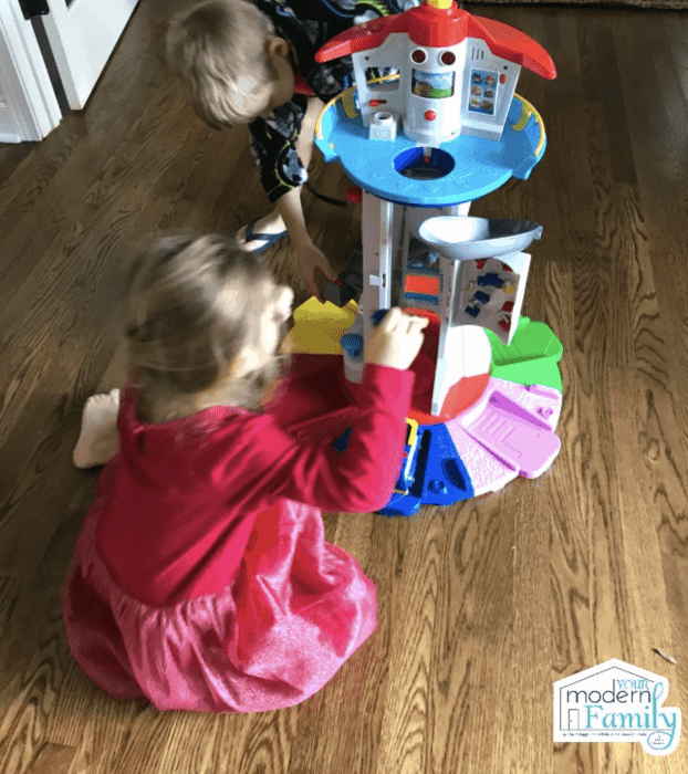 A little girl and a boy playing with a Paw Patrol Tower together.