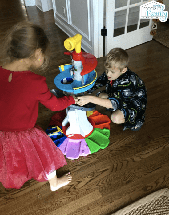 A little girl and boy playing with a Paw Patrol toy.