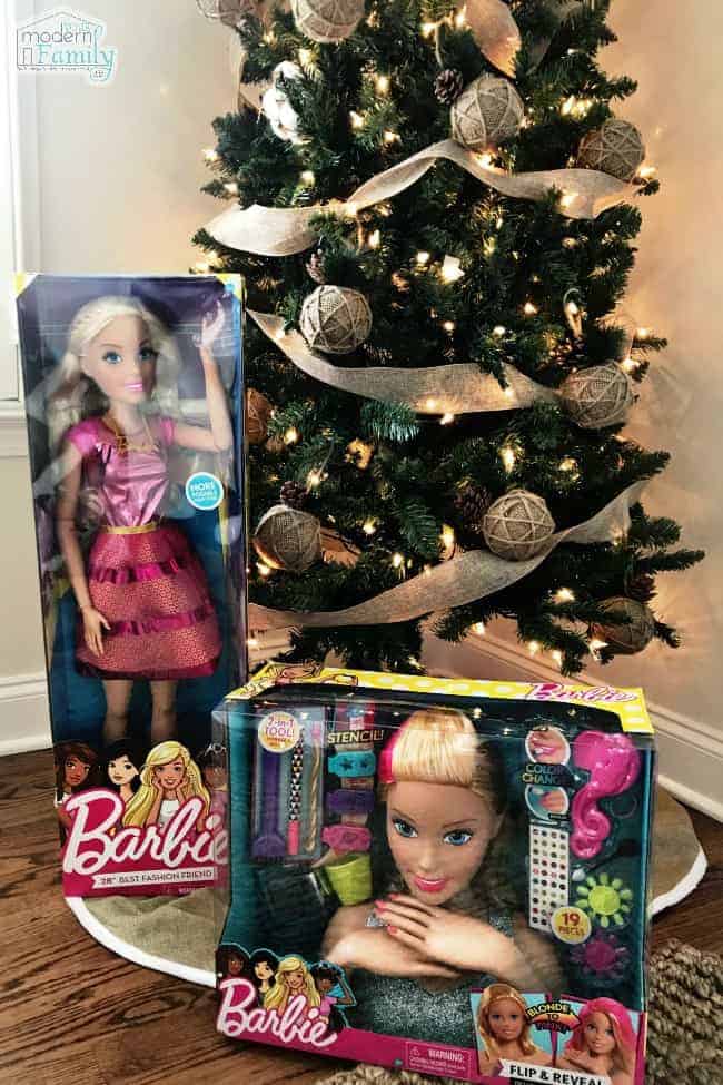 A Christmas tree with unopened Barbie Dolls under it.