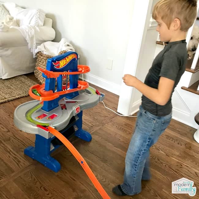 A little boy playing with a Hot Wheel\'s track.