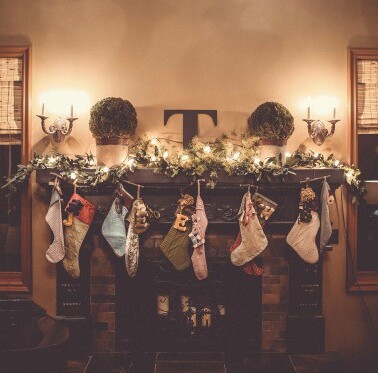 A fireplace decorated with Christmas stockings and garland.