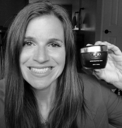 A woman holding a jar of Olay skin care.