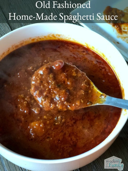 A bowl of meat sauce in a white bowl with a spoon resting on the rim.