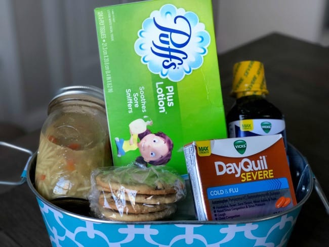 A basket containing a variety of items such as Puff Plus Lotion, DayQuil Severe Cold and Flu and cookies. 