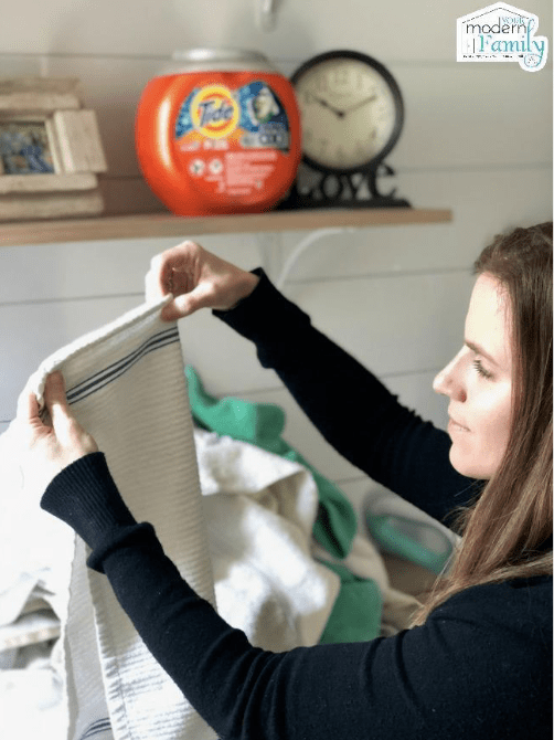 A person folding a white kitchen towel.