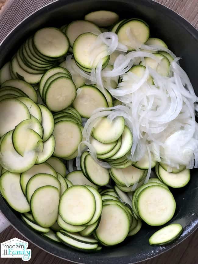 A bowl of cut zucchini and onions in a pot.