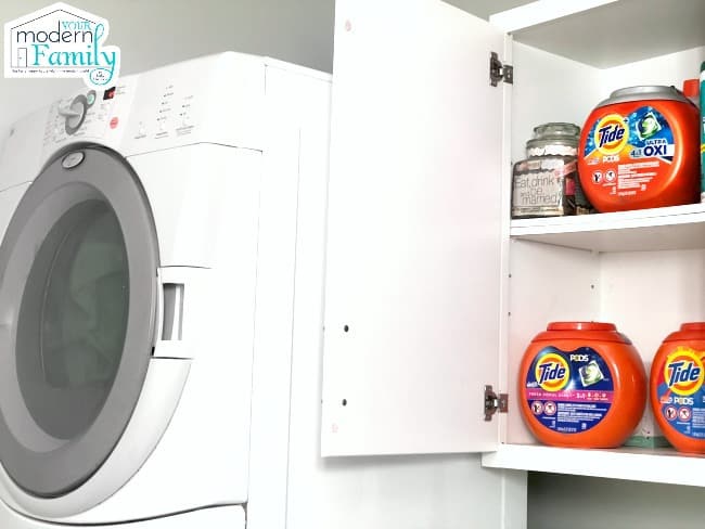 A close up of a laundry room cabinet with a variety of Tide products on the shelf.