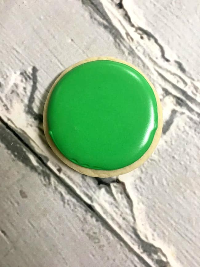 A close up of a green  iced sugar cookie.
