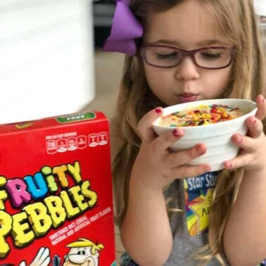A little girl holding a bowl of Fruity Pebbles microwave cake.