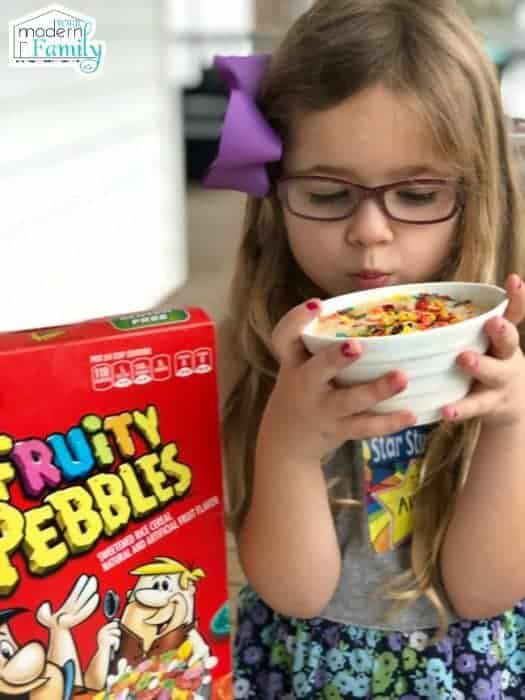 A little girl holding a bowl of Fruity Pebbles microwave cake.