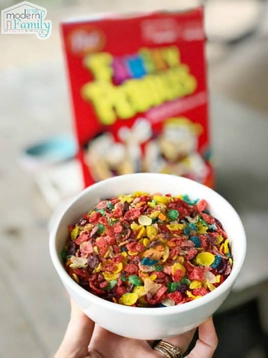 A close up of a bowl of Fruity Pebbles with the box in the background.