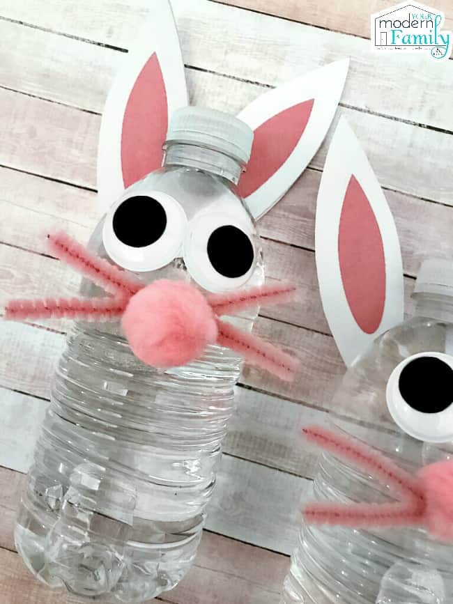 Two water bottles decorated as bunny rabbits lying on a table.