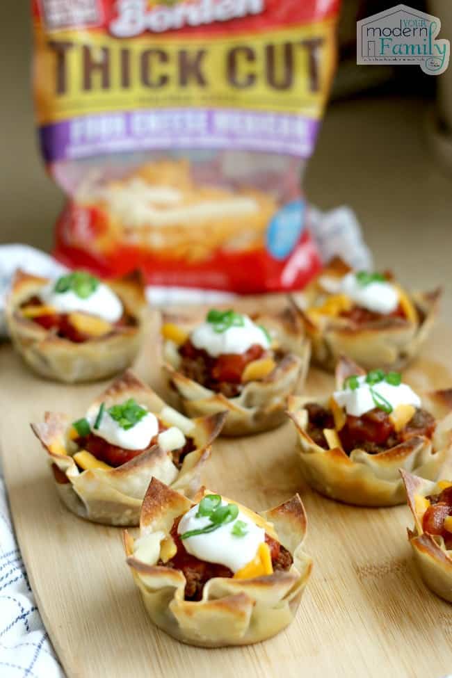 A wooden tray of Taco Casserole Cups with a bag of Borden cheese in the background.