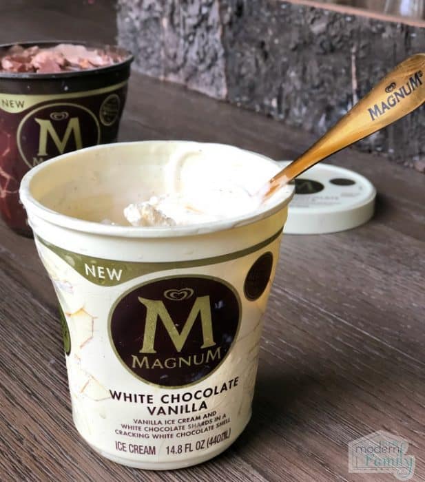 Two containers of Magnum ice cream on a counter with a golden spoon in one of the containers.