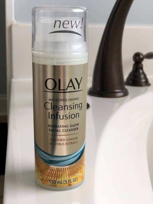 A close up of a bottle of Olay Cleansing Infusion sitting on a bathroom sink.