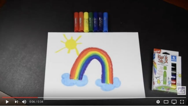 A child\'s painting of a rainbow and sun with a variety of painting sticks above it.