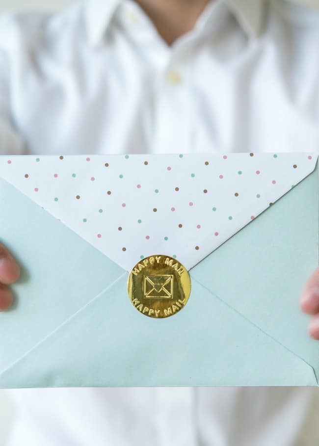 A person in a white shirt holding a greeting card in an envelope.