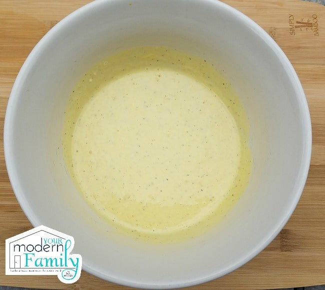 A large white bowl with beaten eggs in it.