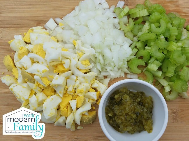 A variety of chopped vegetables and a cup sitting on a table.