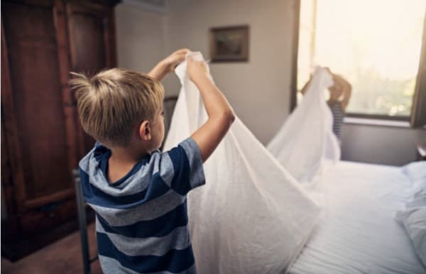 A young boy helping to fold sheets.